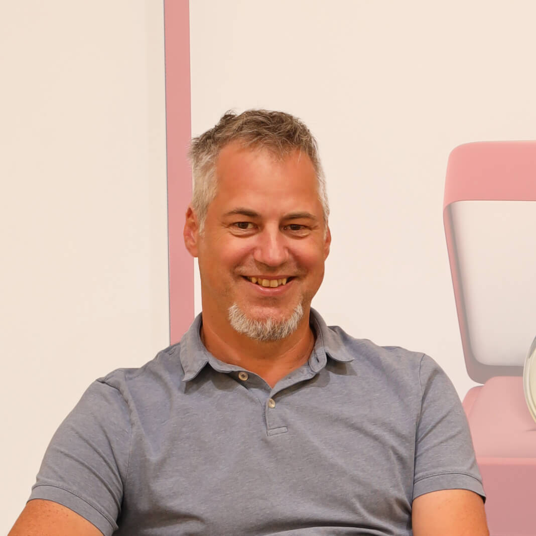 Mst. Günther Moik filialleiter-laechelnd-in-einem-polo-shirt-vor-einem-plakat-in-der-filiale