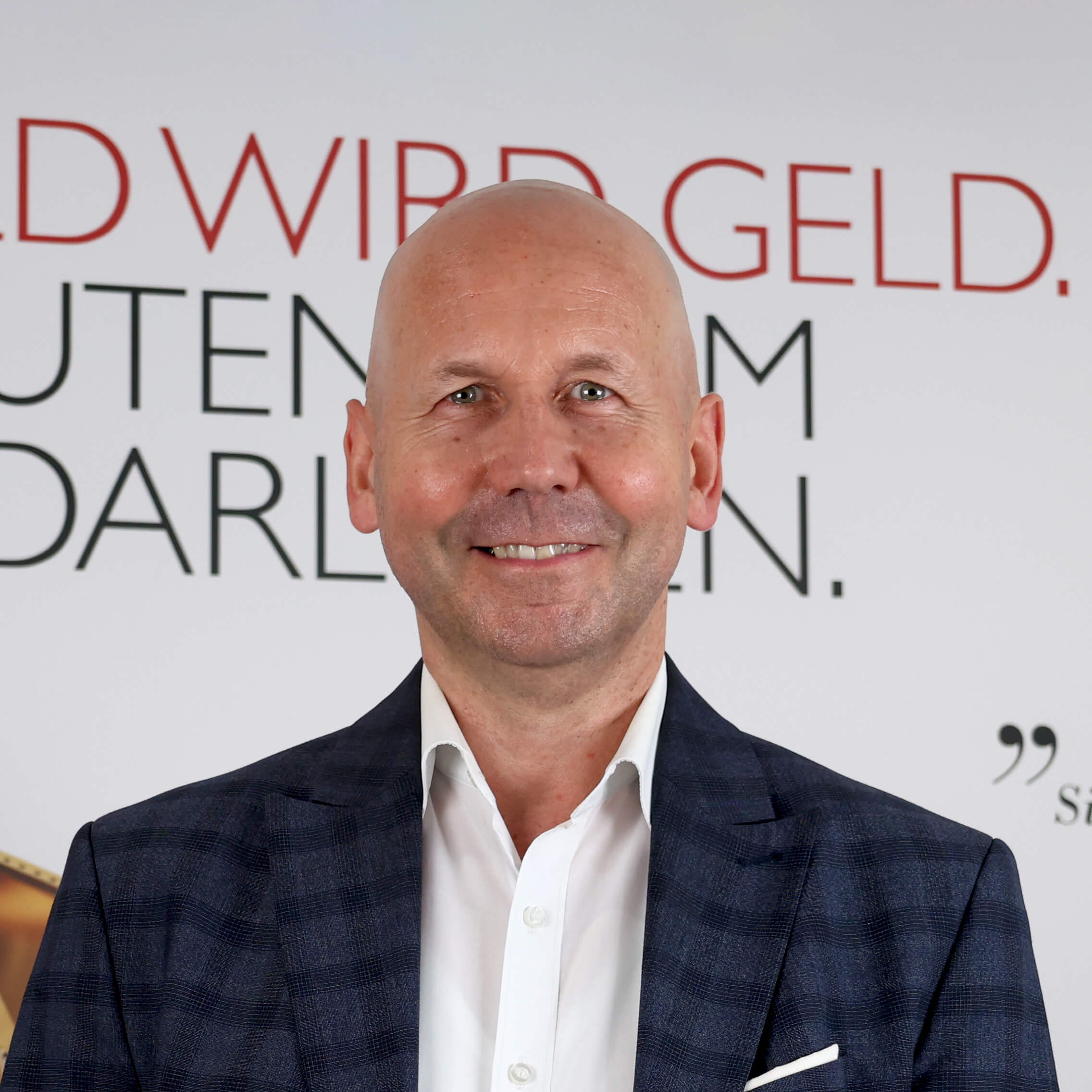 Herfried Seiz filialleiter-laechelnd-vor-poster-in-der-filiale
