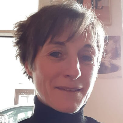 Maria Köberl filialleiterin-laechelnd-in-schwarzem-rollkragen--vor-bildern-in-der-filiale