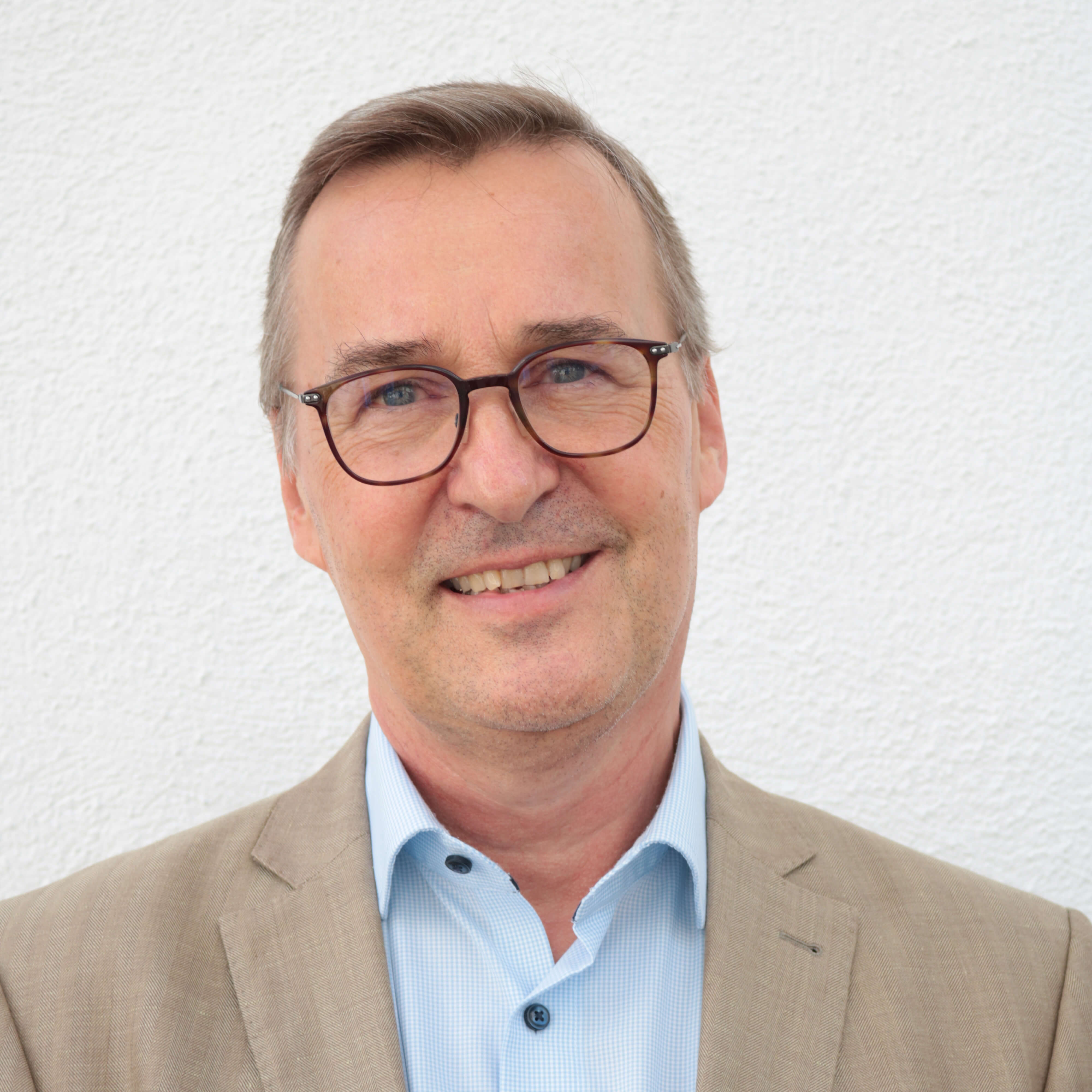 Mag. Clemens Meißner filialleiter-laechelnd-in-einem-braunen-anzug-vor-einer-grauen-wand