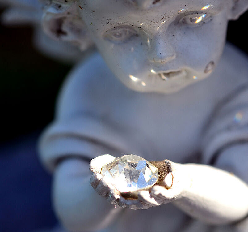 Diamantbestattung - Engel aus Stein hält Edelstein in Händen