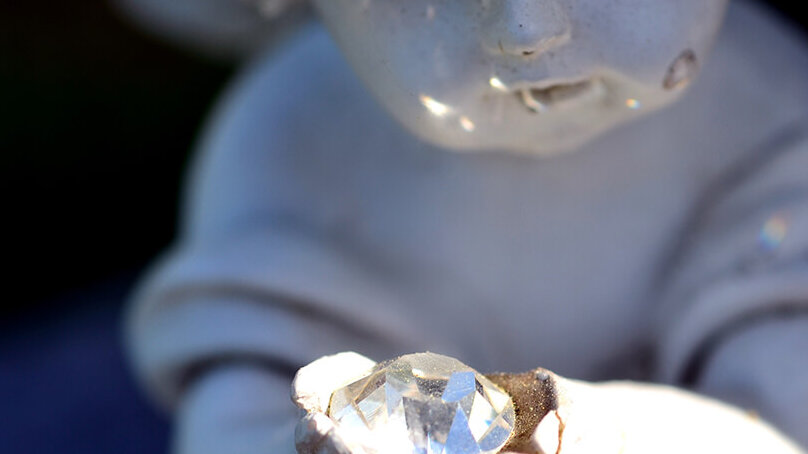 Diamantbestattung - Engel aus Stein hält Edelstein in Händen