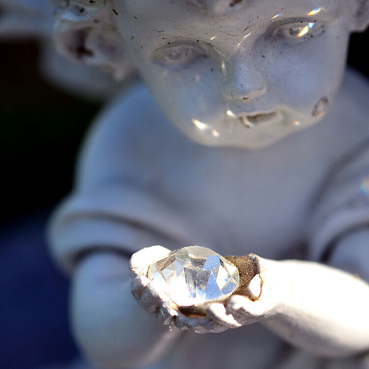 Diamantbestattung - Engel aus Stein hält Edelstein in Händen