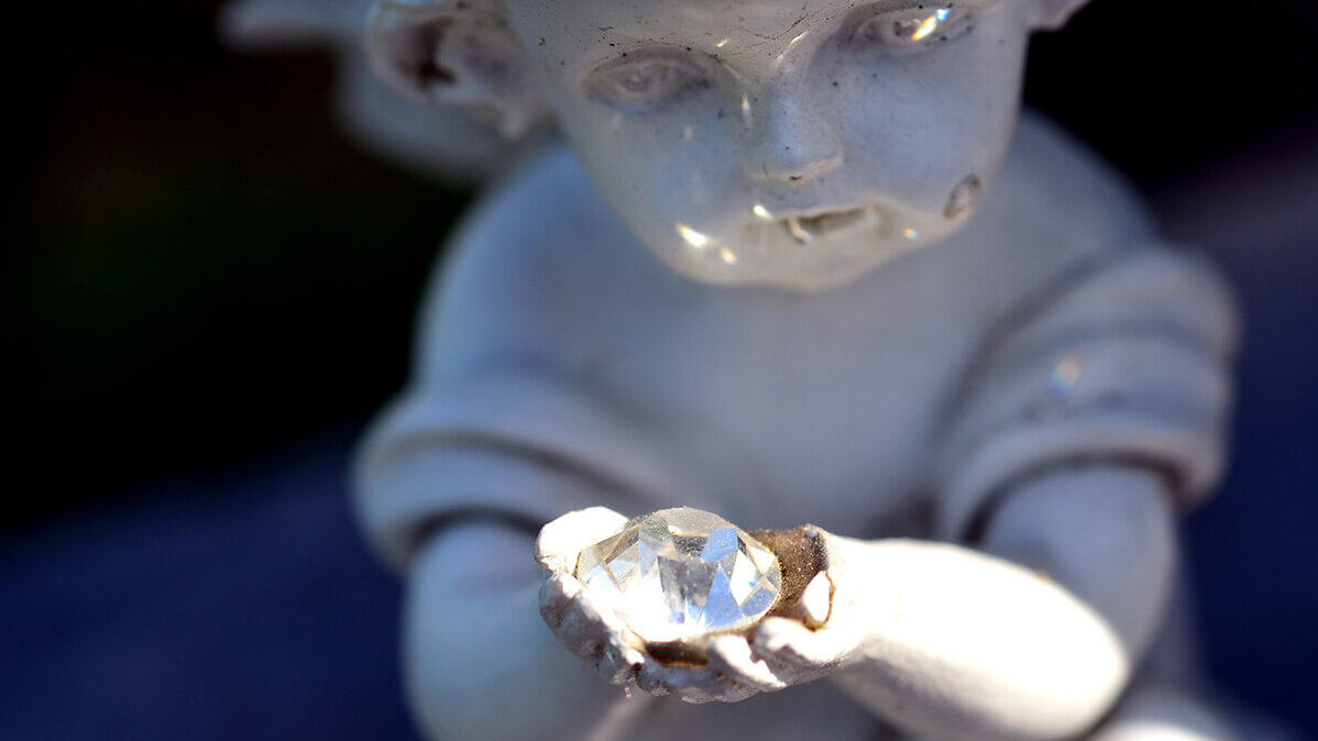 Diamantbestattung - Engel aus Stein hält Edelstein in Händen