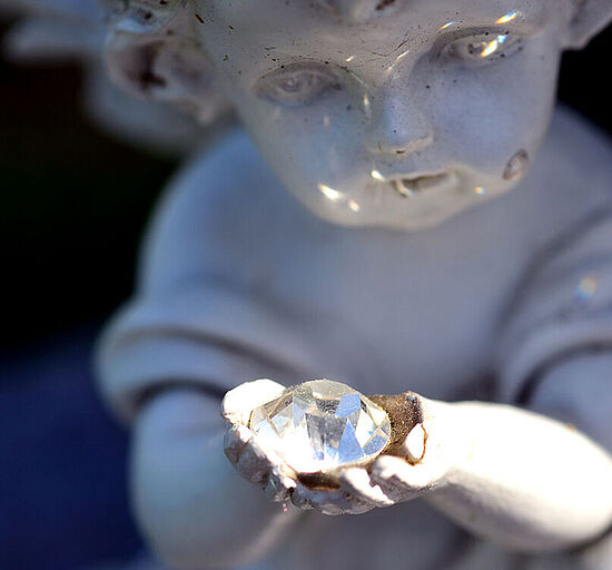 Diamantbestattung - Engel aus Stein hält Edelstein in Händen