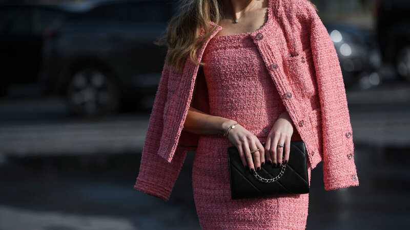 Nobel angezogene  blonde Dame im rosa Kostüm mit Luxushandtasche auf der Straße