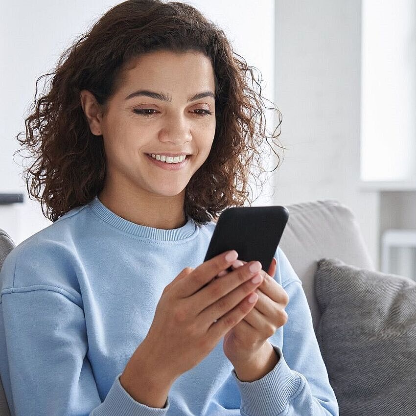 Junge Frau am Sofa mit Smartphone